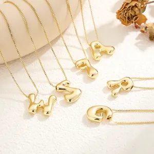 Detail of 18K gold plated bubble letter pendants with glossy finish on box chains