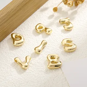 Macro view of polished 18K gold plated bubble letter pendants with side holes for DIY
