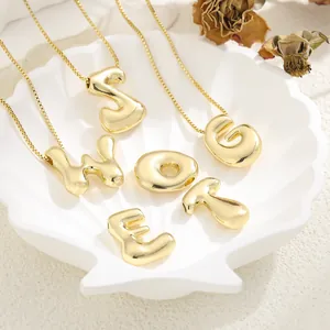 Macro shot of 18K gold plated puffy letter pendants on an elegant shell tray