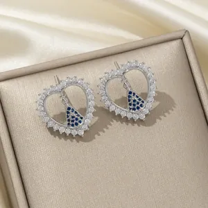Vue macro de boucles d'oreilles cœur en argent et zircons bleus sur écrin cuir
