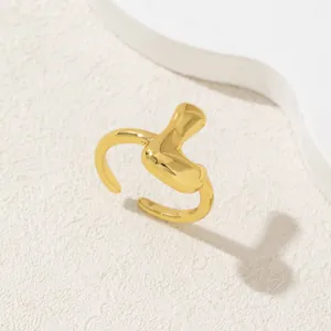 Dettaglio anello dorato regolabile con design minimalista dalle forme organiche