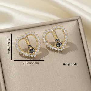 Détail de boucles d'oreilles cœur en cuivre doré avec zircons et icône de la Vierge
