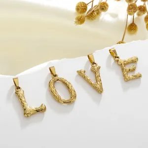 Detail van gouden alfabet hangers L O V E met rustieke schors textuur op stenen achtergrond