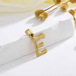 Gedetailleerd beeld van gouden letter E hanger met lavatextuur op stenen basis