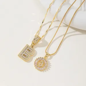 Detailed macro view of two gold letter B pendants with sparkling cubic zirconia settings