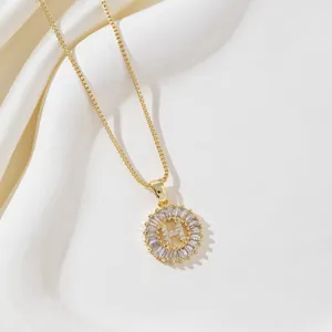 Close-up of golden letter H pendant with micro-paved cubic zirconia on silk background