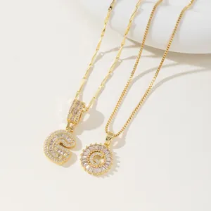 Close-up of two gold letter G necklaces with pavé zircon settings on rope and box chains