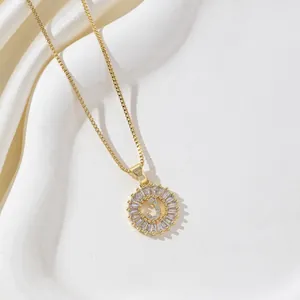 Detail of gold box chain necklace with a baguette zircon letter J round pendant