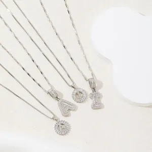 Silver alphabet letter A Q I necklaces with CZ stones on white geometric props