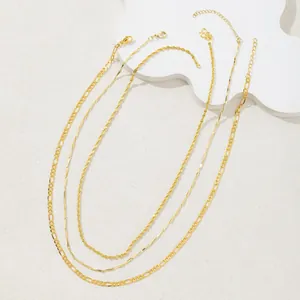 Close-up of gold-plated layering necklaces with Figaro, twisted rope, and geometric links