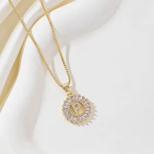 Gold letter P necklace with round cubic zirconia pendant on white silk background