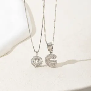 Silver-toned crystal letter G necklace with radiant pavé pendant on a minimalist background