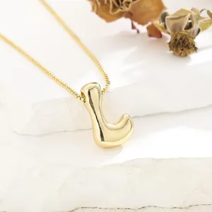 Close-up of gold plated abstract irregular curved pendant necklace on white stone