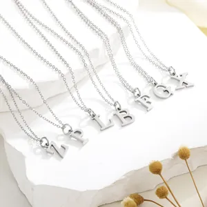 Classic silver-tone titanium steel initial pendant necklace on a stone background