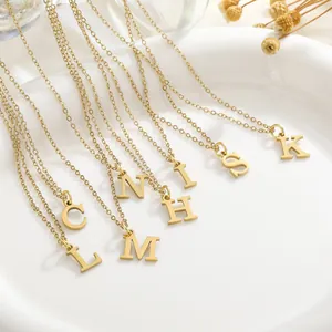 Close-up of gold plated initial pendant necklaces displayed on a white ceramic tray