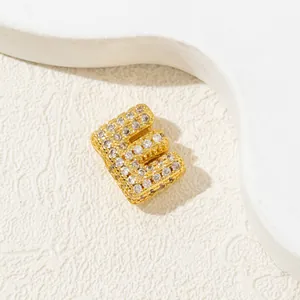 Detailed macro view of gold-plated letter E pendant with cubic zirconia inlay stones