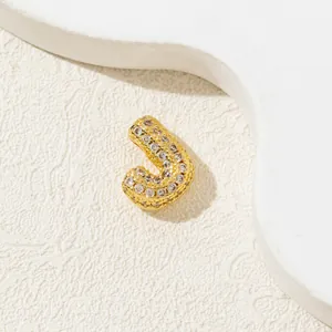 Detailed close-up of golden letter J pendant with shimmering cubic zirconia micro-pave setting