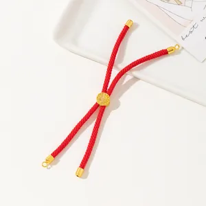 Close-up of handmade red braided cord bracelet with central carved gold bead ornament