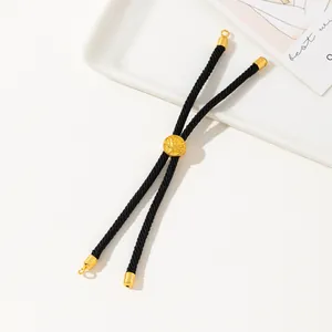 Detail of adjustable black braided cord bracelet with gold charm on a gift card
