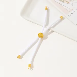 Close-up of white woven rope bracelet with gold adjustable slide buckle and floral engraving
