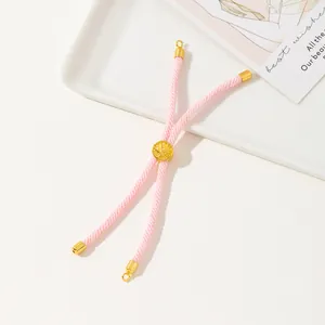 Detail of pink woven cord bracelet featuring adjustable gold slider and metallic ends