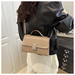 Vue portée du sac carré beige minimaliste avec boucle en métal argenté et sangle