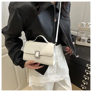 Détail du sac à bandoulière carré crème avec boucle argentée et poignée chic