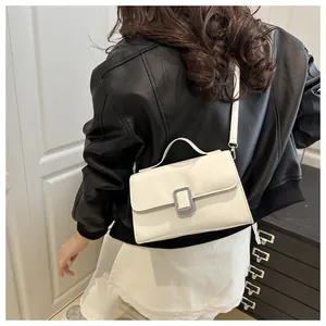 Détail d'un sac bandoulière blanc carré avec boucle argentée porté par un mannequin