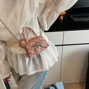 Pink mini crossbody bag with vintage pattern, rhinestone bow, and metal chain strap