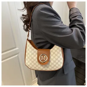 Détail de l'imprimé monogramme M et du logo en métal doré sur le sac en similicuir