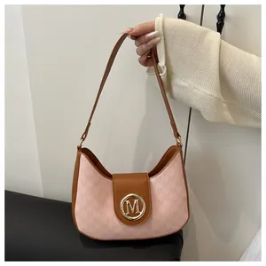 Détail du tissu monogramme rose et cuir marron avec logo M doré sur le sac à main