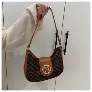 Détail du sac baguette vintage en toile monogrammée avec bordure en cuir marron et logo doré