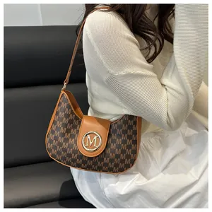Détail du sac porté épaule vintage avec imprimé logo et fermoir doré sur modèle
