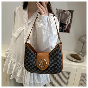 Détail du sac vintage à monogramme avec logo métallique sur fond de dentelle blanche