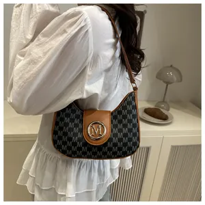Détail du sac hobo en toile avec monogramme M, garniture en cuir marron et boucle dorée