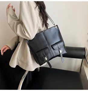 Close-up of black leather tote bag with dual flap pockets and silver metal buckles
