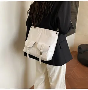 Detail of cream leather tote bag with dual front pockets and buckle straps on a model