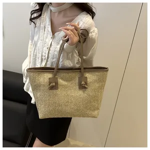 Close-up of a large beige woven straw tote bag with brown knot handles and texture