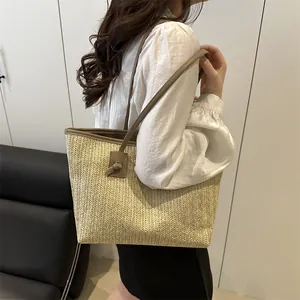 Sac cabas en paille d'été avec bordure en cuir marron et bretelles sur modèle féminin