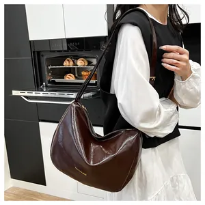 Detailed view of dark brown glossy leather hobo bag with gold metal zipper and strap