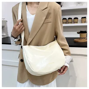 Chic beige leather crescent bag with gold FASHION & BAGS print shown in a lifestyle cafe setting