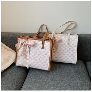 Detail of monogram tote bags with decorative silk scarves on a cozy grey fabric sofa