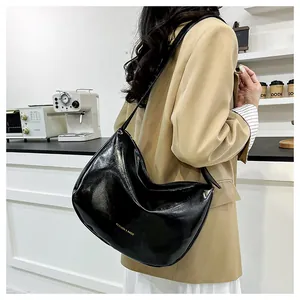Model showing a black glossy hobo bag with gold Fashion & Bags logo in a cafe setting