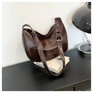 Detail of dark brown hobo bag showing glossy texture and golden adjustable buckle