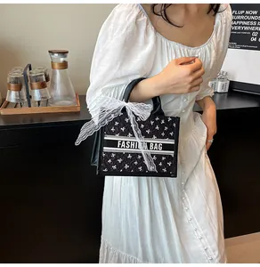 Detail of black tote bag with white bow prints and elegant lace ribbon on the handle