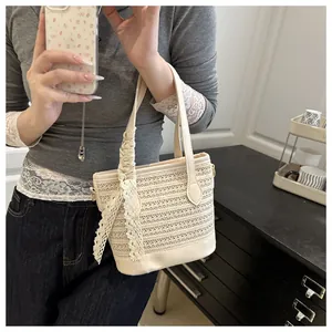 Detail of cream woven straw bucket bag featuring elegant lace ribbon and leather trim