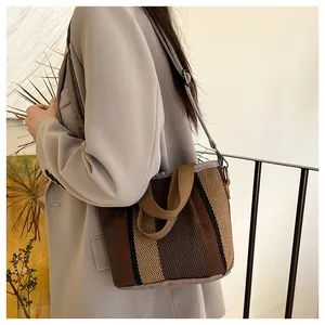 Détail du sac cabas tissé à carreaux porté avec un blazer, montrant les sangles