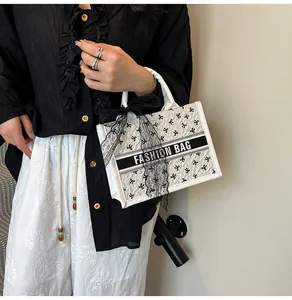 Detail of white tote bag with black bow embroidery and Fashion Bag logo strap