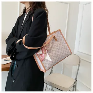 Detail of large printed tote bag with leather trim and decorative silk scarf accessory