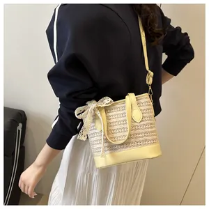 Close-up of woven straw bucket bag with elegant lace bow and yellow leather strap